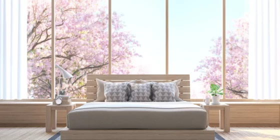 Spring Cleaning for Bedrooms - a tidy bed in front of picture windows showing flowering cherry trees