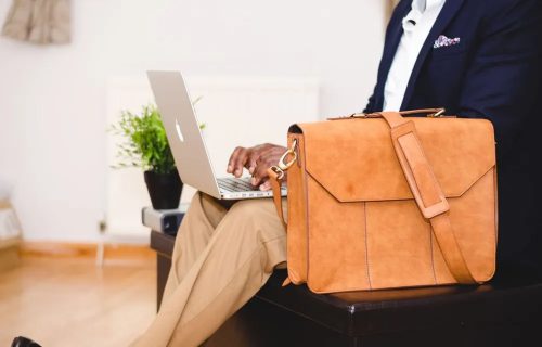 Leather briefcase on table adjacent professional woman using laptop